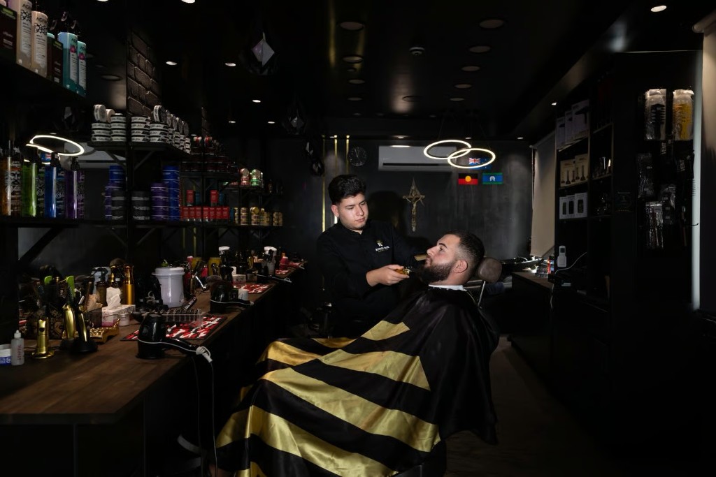 Luxury barbershop interior at Royale Fade in Warragamba — dark walls, gold accents, and barber at work.